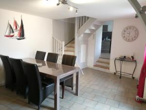 a dining room with a wooden table and black chairs at Entre MER et FORET in Le Tréport