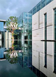 een glazen gebouw met reflectie in het water bij Intercontinental Shenzhen Dameisha Resort, an IHG Hotel in Shenzhen