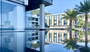 eine Reflexion eines Gebäudes in einem Wasserpool in der Unterkunft Intercontinental Shenzhen Dameisha Resort, an IHG Hotel in Shenzhen