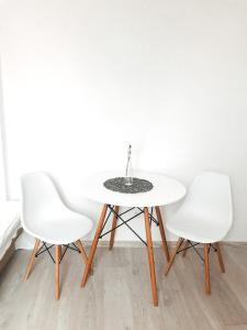 two white chairs and a table with a vase on it at Przytulny domek in Mielno +12 photos