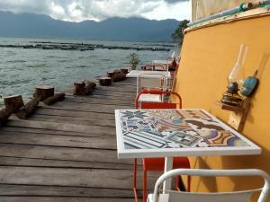 a wooden dock with tables and chairs on the water at Hotel Maninjau Indah - The Lakeside Resort in Maninjau