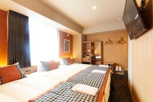 a hotel room with two beds and a television at hotel MONday Asakusa in Tokyo