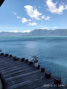 a wooden dock in the middle of a body of water at Hotel Maninjau Indah - The Lakeside Resort in Maninjau