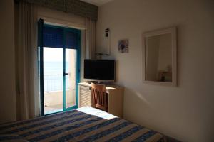 a bedroom with a bed and a television and a window at Sea Palace Hotel in Marina di Fuscaldo