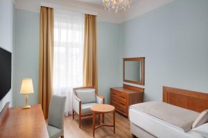 a bedroom with a bed and a desk and a chair at Ensana Hvězda - Imperiál - Neapol in Mariánské Lázně