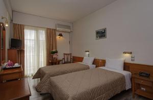 a hotel room with two beds and a television at Hotel Nefeli in Volos