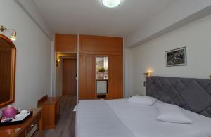 a bedroom with a white bed and a wooden cabinet at Hotel Nefeli in Volos