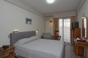 a bedroom with a white bed and a television at Hotel Nefeli in Volos