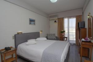 a bedroom with a large white bed and a window at Hotel Nefeli in Volos