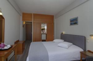 a bedroom with a large white bed and wooden cabinets at Hotel Nefeli in Volos