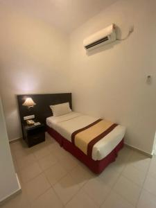 a bedroom with a bed and a air conditioner on the wall at Swan Garden Hotel in Pasir Gudang