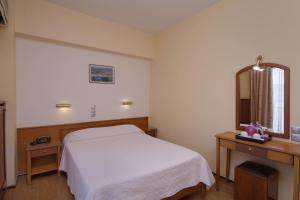a bedroom with a white bed and a mirror at Hotel Nefeli in Volos