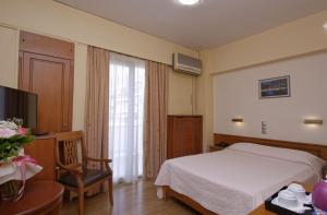 a bedroom with a bed and a desk and a television at Hotel Nefeli in Volos