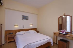 a bedroom with a white bed and a mirror at Hotel Nefeli in Volos