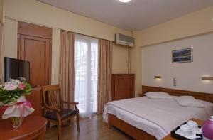 a hotel room with a bed and a chair and a television at Hotel Nefeli in Volos