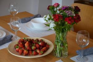 a table with a plate of strawberries and a vase of flowers at INES apartament two Levels 105m2 in the Old Town wi-fi, netflix in Olsztyn