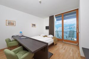 Habitación con escritorio, cama y balcón. en Hotel Venezia en Malcesine