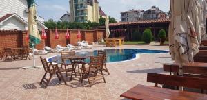 a patio with a table and chairs next to a pool at Hotel Laguna - Guest House in Primorsko