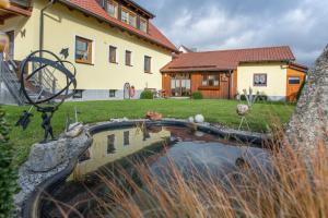 ein Haus mit einem Teich vor einem Haus in der Unterkunft Ferienwohnung Forster in Moosbach