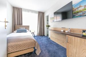 ein Hotelzimmer mit einem Bett und einem Flachbild-TV in der Unterkunft Hotel Tivoli in Schlieren