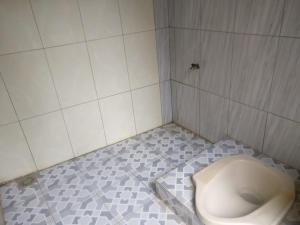 a bathroom with a toilet in a tiled floor at Homestay Kurnia in Bantul