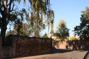 a street with a brick wall and trees and a fence at Ferienwohnung Spatzennest in Edesheim in Edesheim