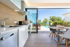 una cucina con tavolo e vista sulla piscina di Tamarells B By homevillas360 a Son Serra de Marina