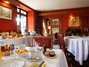 uma sala de jantar com duas mesas com toalhas de mesa brancas e comida em Hôtel de Londres em Fontainebleau