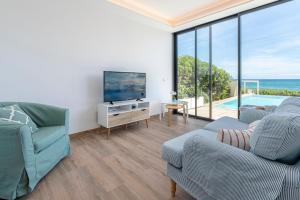 Sala de estar con sofá y TV y vistas al océano en Tamarells A By homevillas360, en Son Serra de Marina