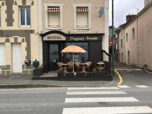 an outdoor cafe with umbrellas on the sidewalk at Hôtel Duguay-Trouin in Cancale