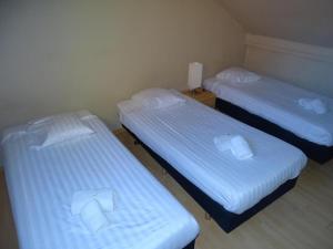 2 camas en una habitación pequeña con sábanas blancas en Condo Gardens Leuven - Large One Bedroom, en Lovaina