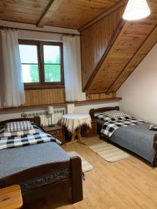 two beds in a room with wooden ceilings and windows at Agroturystyka u Królów in Nowe Guty