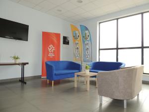a waiting room with blue chairs and a table and surfboards at Hostel Załogowa in Gdańsk