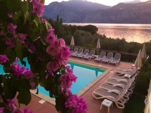 a swimming pool with lounge chairs and a view of a lake at Hotel Roma Aparthotel in Malcesine