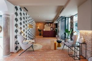a lobby with white chairs and a brick wall at Hotel Cetina Sevilla in Seville
