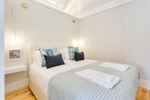 um quarto branco com uma cama com almofadas azuis em DA'HOME - Rola Art Work Studio no Porto