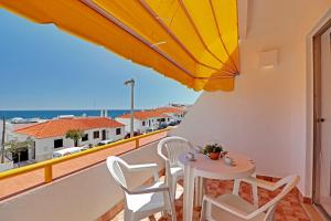 - un balcon avec une table, des chaises et un parasol dans l'établissement Albufeira Ocean View by Homing, à Albufeira