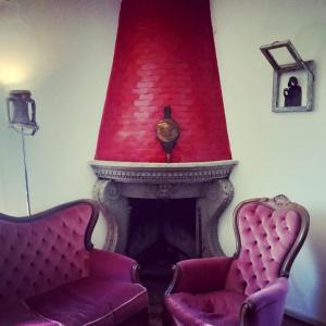 twee stoelen voor een open haard met een rood plafond bij La Casa del Grillo in Viterbo
