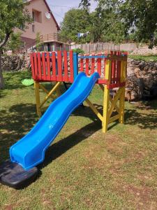 a playground with a blue slide and a wooden bench at Apartman Nika in Otočac