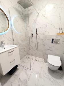 biała łazienka z toaletą i przeszkloną kabiną prysznicową w obiekcie Apartament Alicja w Sztutowie