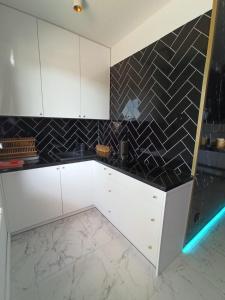 a kitchen with white cabinets and a black tile wall at Apartament Alicja in Sztutowo