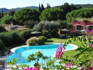a pool in a garden with trees and flowers at Hotel Mariposas in Villasimius