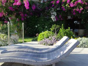 a metal bench in a garden with purple flowers at Hotel Mariposas in Villasimius