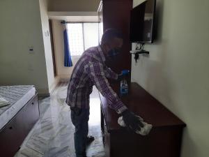Ein Mann mit Maske und Handschuhen, der in eine Schublade greift. in der Unterkunft Hotel Paradise Inn in Tiruppūr