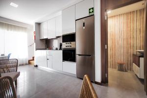 a kitchen with white cabinets and a stainless steel refrigerator at Terrazzos do Prado - Vista Ria de Aveiro in Costa Nova