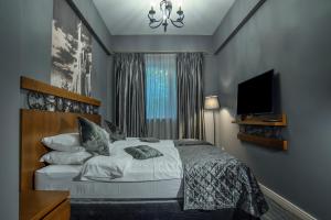 a bedroom with a bed with a television and a window at Badagoni Boutique Hotel Rustaveli in Tbilisi City