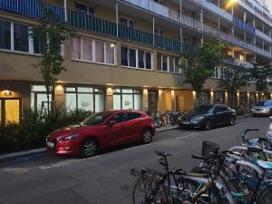 ein rotes Auto, das vor einem Gebäude mit Fahrrädern geparkt ist in der Unterkunft Gabriel´s Apartments in Wien