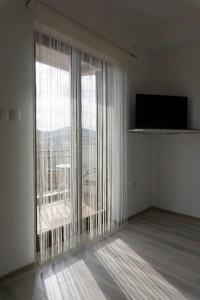 une chambre vide avec une grande fenêtre et une télévision dans l'établissement Apartmani Ivković+, à Trebinje