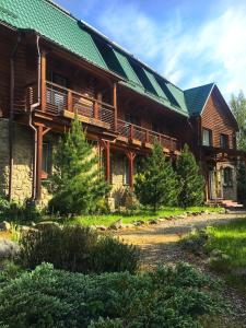 une grande maison en bois avec un toit vert dans l'établissement Vilni Vitry, à Osmoloda