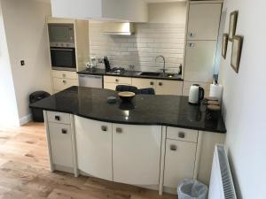 a kitchen with white cabinets and a black counter top at Wagtail Cottage in Tarporley